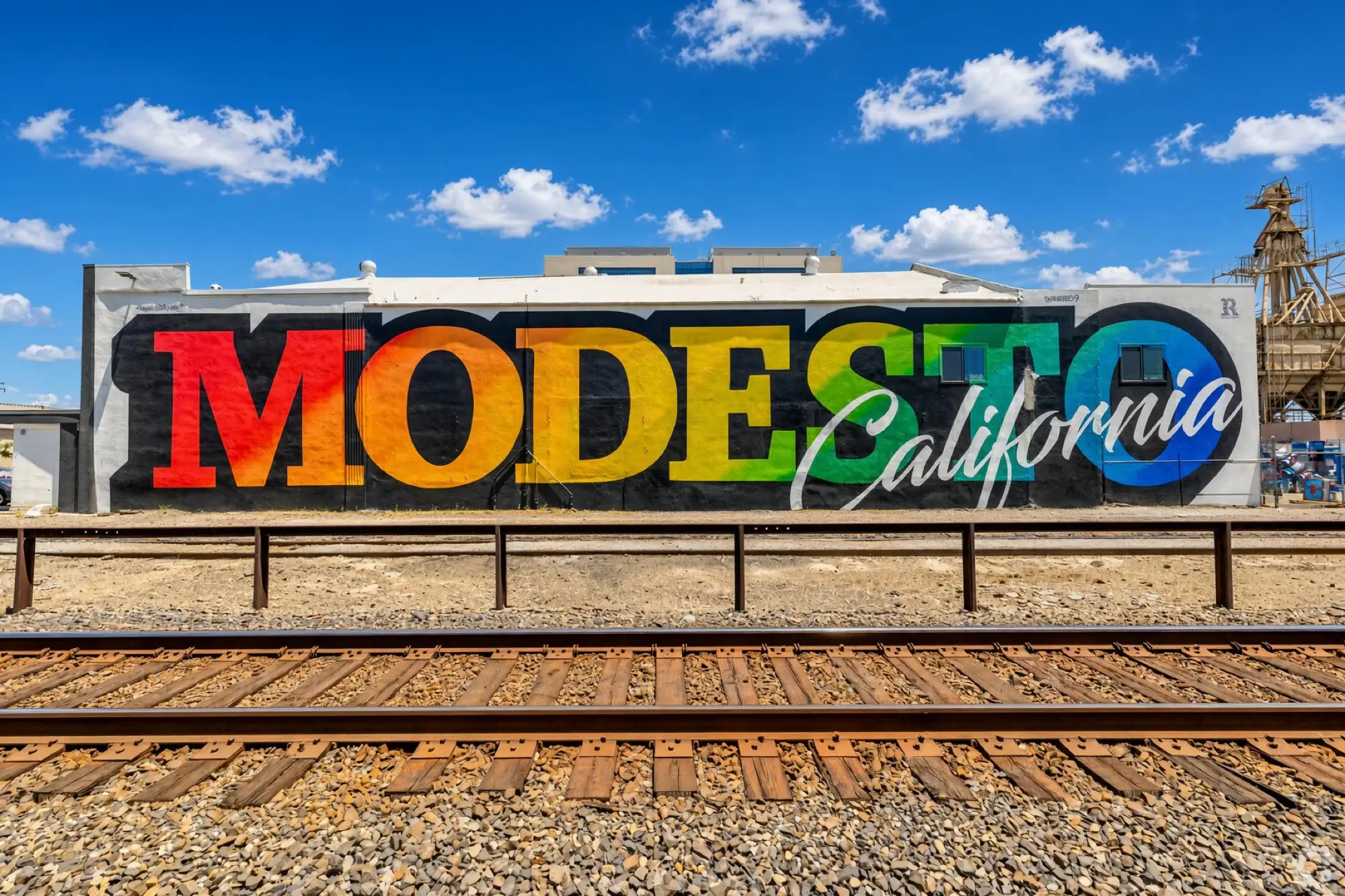 Un mural de colores que dice “Modesto California” en un edificio junto a las vías del tren